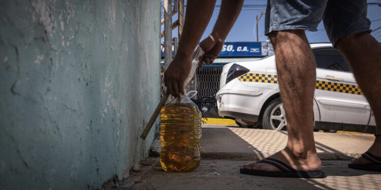 MARACAIBO (VENEZUELA), 06/10/2023.- Un hombre vende gasolina de contrabando, el 29 de septiembre de 2023, en Maracaibo (Venezuela). Las actividades ilícitas han ganado terreno en la economía de Venezuela, donde el narcotráfico, la extorsión y el comercio ilegal de oro y combustible generaron 9.402 millones de dólares en 2022, según cálculos independientes, lo que expertos atribuyen a la expansión de grupos irregulares organizados ante la "anuencia" del Estado. EFE/ Henry Chirinos