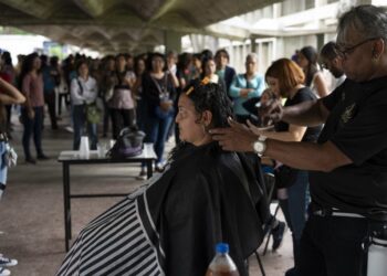 Volunteers cut donors' hair during a human and animal hair donation campaign promoted by the environmental movement "Proyecto Sirena" at the Central University of Venezuela (UCV) in Caracas on October 6, 2023. Hundreds of Venezuelans come to get their hair cut, some with their pets, to support the initiative that aims to use human and animal hair to contribute to the cleanup of Lake Maracaibo, in Zulia State, highly contaminated by constant oil spills. (Photo by Yuri CORTEZ / AFP)