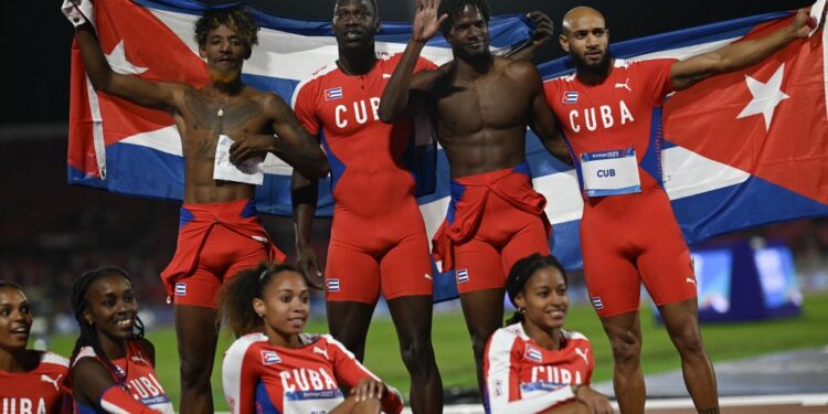 Cuba's men's team (top) celebrates next to the women's team after winning the silver and gold medals, respectively, in the 4 x 100m relay finals of the Pan American Games Santiago 2023 at the National Stadium in Santiago on November 2, 2023. (Photo by MAURO PIMENTEL / AFP)