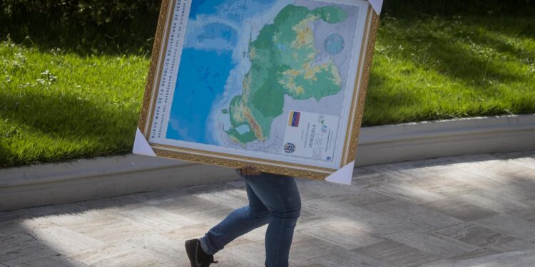 -FOTODELDÍA- AME2481. CARACAS (VENEZUELA), 06/12/2023.- Un hombre carga hoy un cuadro del mapa de Venezuela con la adhesión del Esequibo, en uno de los jardines del Palacio Federal Legislativo en Caracas (Venezuela). La Asamblea Nacional (AN, Parlamento) de Venezuela, controlada por el chavismo, prevé aprobar dentro de una semana la ley de anexión del territorio en disputa con Guyana, en cumplimiento del referendo unilateral celebrado el domingo relacionado con este conflicto, aseguró el presidente de la Cámara, Jorge Rodríguez. EFE/ MIGUEL GUTIERREZ