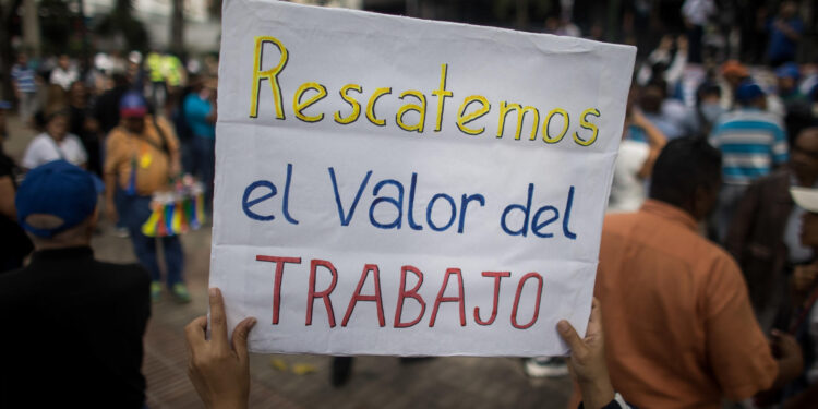 AME082. CARACAS (VENEZUELA), 15/01/2024.- Una persona sostiene un cartel de protesta durante una manifestación de maestros, respaldados por trabajadores de otros sectores, contra los bajos salarios y para exigir mejoras laborales, hoy, en Caracas (Venezuela). Cientos de maestros en Venezuela volvieron a las calles este lunes, cuando se conmemora su día en el país, con el objetivo de exigir al Gobierno de Nicolás Maduro la reanudación de las negociaciones para una nueva convención colectiva. Esta es la segunda jornada de manifestaciones de trabajadores de este año, que comenzaron el pasado 9 de enero. EFE/ Miguel Gutiérrez