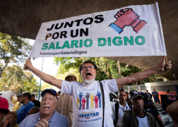 CARACAS (VENEZUELA), 09/01/2023.- Un trabajador carga una pancarta que dice "juntos por un salario digno" durante una protesta para exigir aumento salarial y de pensiones, hoy, en Caracas (Venezuela). Cientos de trabajadores públicos protestaron este martes en Caracas y en buena parte de Venezuela contra los "salarios de hambre" que aseguran devengar, y para exigir ingresos "dignos" que les permitan cubrir sus necesidades básicas, así como por el "hostigamiento laboral". EFE/ Rayner Peña R.