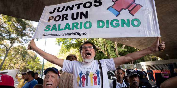 CARACAS (VENEZUELA), 09/01/2023.- Un trabajador carga una pancarta que dice "juntos por un salario digno" durante una protesta para exigir aumento salarial y de pensiones, hoy, en Caracas (Venezuela). Cientos de trabajadores públicos protestaron este martes en Caracas y en buena parte de Venezuela contra los "salarios de hambre" que aseguran devengar, y para exigir ingresos "dignos" que les permitan cubrir sus necesidades básicas, así como por el "hostigamiento laboral". EFE/ Rayner Peña R.