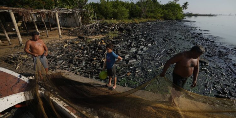 Pescadores estiran sus redes en la ribera del Lago de Maracaibo contaminado con petróleo y desechos en el agua, en San Francisco, Venezuela, el miércoles 9 de agosto de 2023. La contaminación en torno al lago, uno de los más grandes de América Latina, es resultado de décadas de excesiva explotación petrolera en su lecho, mantenimiento inadecuado y falta de inversión en una infraestructura obsoleta, según ambientalistas. (AP Foto/Ariana Cubillos)