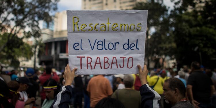 AME632. CARACAS (VENEZUELA), 18/01/2024.- Una persona muestra un cartel de protesta durante una manifestación de trabajadores que exigen mejores salarios y condiciones laborales, el 15 de enero de 2024, en Caracas (Venezuela). Los trabajadores públicos de Venezuela inician otro año de protestas contra los "salarios de hambre", una lucha que planean intensificar hasta que el clamor por un ingreso que satisfaga sus necesidades reciba, finalmente, una respuesta de las autoridades acorde a sus demandas, dijeron sindicalistas a EFE. Cientos de trabajadores llevaron a cabo el lunes la segunda jornada de manifestaciones de 2024, que finalizó con el anuncio del presidente Nicolás Maduro de un aumento de 30 a 60 dólares de una bonificación mensual sin incidencia en el cálculo de beneficios como las prestaciones, mientras que el salario mínimo se mantiene, desde marzo de 2022, en 130 bolívares, hoy 3,6 dólares al mes. EFE/ Miguel Gutiérrez