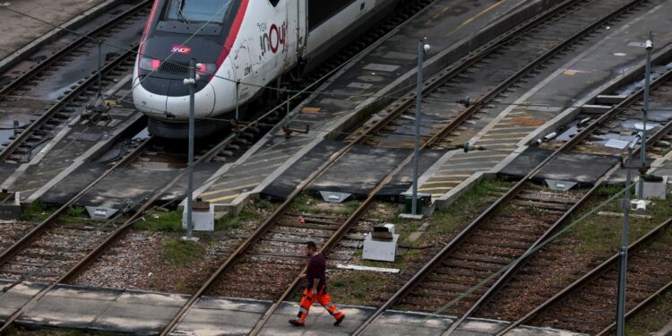 An employee walks on the Charenton-le-pont railway yard near an InOui high-speed TGV train, amid a ticket controller strike in Paris on February 16, 2024. Train stations anticipate possible chaos for the school holiday weekend: only one in two TGVs will run from February 16 to 18, 2024, due to a controllers' strike, according to the SNCF. (Photo by Ian LANGSDON / AFP)