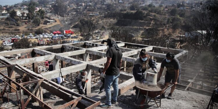 Residents remove debris from burned houses after the forest fires in Villa Independencia, Viña del Mar, Chile, on February 5, 2024. The death toll from central Chile's blazing wildfires climbed to at least 112 people on Sunday, after President Gabriel Boric warned the number would rise "significantly" as teams search gutted neighborhoods. (Photo by Javier TORRES / AFP)