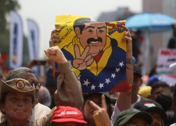 AME2269. CARACAS (VENEZUELA), 25/03/2024.- Una persona levanta un cartel con un dibujo del presidente venezolano, Nicolás Maduro, durante una concentración de simpatizantes del oficialismo que se reúnen este lunes para mostrar su apoyo y acompañar a su candidato a las próximas elecciones del 28 de julio, el actual mandatario Nicolás Maduro, a oficializar su aspiración ante el Consejo Nacional Electoral (CNE), en Caracas (Venezuela). El proceso de presentación de candidaturas para las presidenciales concluye este lunes, con la inscripción de Maduro, mientras que la oposición mayoritaria espera poder postular a Corina Yoris, su aspirante ante la inhabilitación de María Corina Machado, ganadora de las primarias de octubre. EFE/ Miguel Gutiérrez