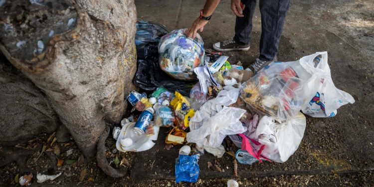 AME8341. CARACAS (VENEZUELA), 13/03/2024.- Un hombre remueve una pila de basura este miércoles, en Caracas (Venezuela). El 51,9 % de los hogares de Venezuela sufrieron, en 2023, una "pobreza multidimensional", caracterizada por bajos ingresos, carencias en los servicios básicos, deterioro de la educación, entre otros aspectos, según la Encuesta de Condiciones de Vida (Encovi), cuyos resultados fueron presentados este miércoles en Caracas. EFE/ Miguel Gutiérrez