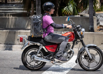 AME5448. CARACAS (VENEZUELA), 05/03/2024.- Un repartidor de servicio a domicilio conduce su motocicleta por una calle el 4 de marzo de 2024, en Caracas (Venezuela). El reparto a domicilio registra un crecimiento sostenido desde 2020 en Venezuela, donde miles de personas han mejorado sus ingresos luego de haberse sumado a este sector, que recientemente logró echar atrás una serie de medidas que buscaban su regulación, como el cobro del 1 % sobre estos servicios. Datos suministrados a EFE por la Cámara Venezolana de Comercio Electrónico (Cavecom-e) dan cuenta de más de 200.000 repartidores con motocicletas -el principal medio de transporte usado en el país para estas entregas- incorporados al sector del 'delivery'. EFE/ Rayner Peña R.