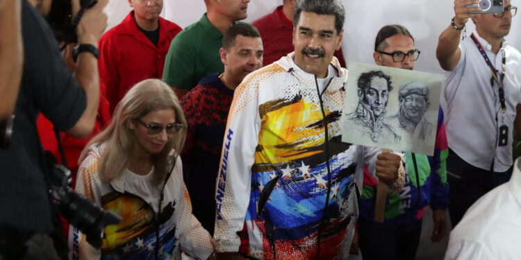 AME2344. CARACAS (VENEZUELA), 25/03/2024.- El mandatario de Venezuela, Nicolás Maduro (c), acompañado de su esposa, Cilia Flores, llega este lunes a la sede del Consejo Nacional Electoral (CNE) para hacer oficial su candidatura a las presidenciales del próximo 28 de julio, en las que competirá por un tercer período en el poder, que ocupa desde 2013, en Caracas (Venezuela). El líder chavista acudió a la sede del ente electoral tras participar en una marcha convocada por el gobernante Partido Socialista Unido de Venezuela (PSUV) en respaldo a su inscripción, con la que se convierte en el décimo político en oficializar su aspiración, a pocas horas de que concluya el plazo establecido en el cronograma para la presentación de candidaturas. EFE/ Rayner Peña R.