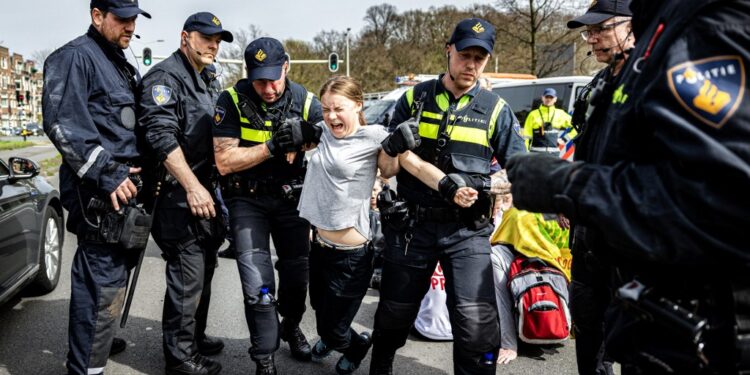 Swedish climate activist Greta Thunberg (C) is arrested during a climate march against fossil subsidies near the highway A12 in the Hague, on April 6, 2024. Dozens of police officers, some on horseback, blocked protesters from reaching the A12 arterial highway into the Dutch seaside city, the scene of previous actions organised by the Extinction Rebellion (XR) group (Photo by Ramon van Flymen / ANP / AFP) / Netherlands OUT