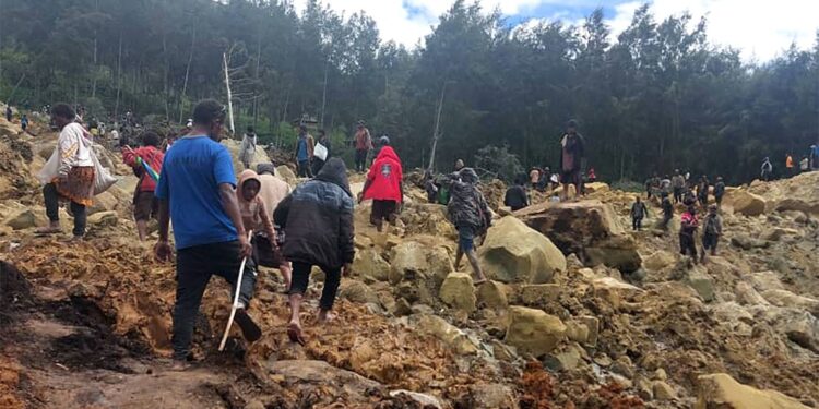 This handout photo by the International Organization for Migration (IOM) on May 25, 2024 shows locals walking on top of a landslide at Yambali Village in the region of Maip Mulitaka, in Papua New Guinea's Enga Province. Rescue teams began arriving at the site of a massive landslide in Papua New Guinea's remote highlands on May 25, helping villagers search for the scores of people feared dead under the towering mounds of rubble and mud. (Photo by BENJAMIN SIPA / International Organization for Migration / AFP) / RESTRICTED TO EDITORIAL USE - MANDATORY CREDIT "AFP PHOTO / International Organization for Migration (IOM) / Benjamin Sipa " - NO MARKETING NO ADVERTISING CAMPAIGNS - DISTRIBUTED AS A SERVICE TO CLIENTS