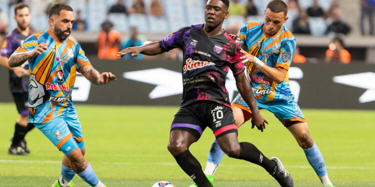 AME8484. CARACAS (VENEZUELA), 23/05/2024.- El exfutbolista neerlandés Clarence Seedorf (c) de Vergatarios disputa el balón con Giancarlo Maldonado (d) de Vikingos del Caribe este jueves, en un partido de fútbol 9 de la Liga Monumental, en el estadio Monumental Simón Bolívar de Caracas (Venezuela). Los futbolistas venezolanos Alejandro 'Lobo' Guerra, Ángel Chourio, Armando Maita y Richard Blanco fueron los protagonistas este jueves de la primera jornada de la Liga Monumental, un atípico campeonato en el que varias estrellas retiradas competirán hasta el 30 de junio, en la modalidad de fútbol 9. EFE/ Rayner Peña R.