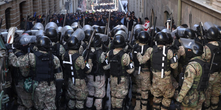 AME6897. LA PAZ (BOLIVIA), 26/06/2024.- Integrantes de la Policía Militar se forman frente a simpatizantes del presidente Luis Arce durante una protesta contra los militares que tomaron la sede del Gobierno de Bolivia, este miércoles en La Paz (Bolivia). Este miércoles un grupo de militares encabezados por el que hasta hoy era el Comandante General del Ejército de Bolivia, Juan José Zuñiga, tomó la plaza y con un tanque tiró la puerta de la sede del Gobierno del presidente Luis Arce quien calificó la acción como un "intento de golpe de Estado". EFE/ Luis Gandarillas