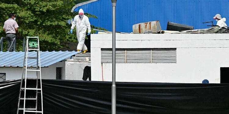 A forensic worker walks on top of a container inside the city morgue in Guayaquil, Ecuador on June 13, 2024. - In the surroundings of Guayaquil's morgue, the mourners must not only deal with their loss, but with the nauseating smell from the forensic center, packed with bodies, many, victims of a painful war imposed by drug trafficking in Ecuador. (Photo by MARCOS PIN / AFP)