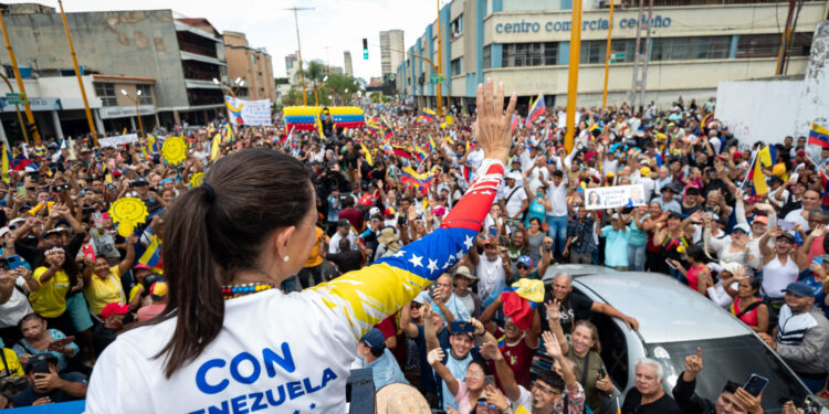 AME1670. VALENCIA (VENEZUELA), 13/07/2024.- La lider de la oposición, María Corina Machado (i) saluda a simpatizantes durante un acto de campaña este sábado en la ciudad de Valencia, estado de Carabobo (Venezuela). La líder opositora de Venezuela María Corina Machado sorteó este sábado "obstáculos" en su viaje hacia Valencia, estado Carabobo, al superar dos cierres de la autopista que conduce hacia esa ciudad, donde encabezará un acto de campaña junto al candidato presidencial Edmundo González Urrutia, de cara a las elecciones del 28 de julio. EFE/ Ronald Peña