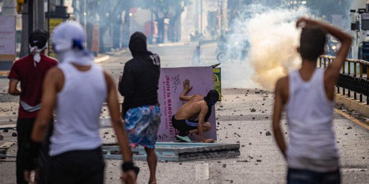 AME6327. CARACAS (VENEZUELA), 29/07/2024.- Manifestantes se enfrentan a la Guardia Nacional Bolivariana (GNB), por los resultados de las elecciones presidenciales este lunes, en Caracas (Venezuela). Este lunes, miles de ciudadanos han salido para protestar contra los resultados anunciados por el Consejo Nacional Electoral (CNE), que otorga al presidente Maduro el 51,2 % de los votos, un dato cuestionado por la oposición y por buena parte de la comunidad internacional. EFE/ Henry Chirinos