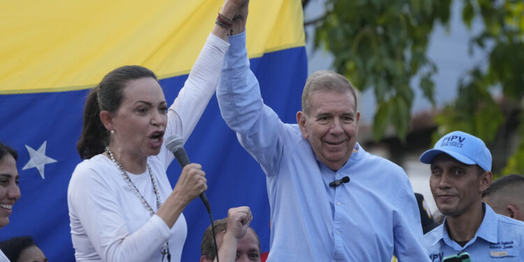 Venezuelan opposition leader Mariana Corina Machado and presidential candidate Edmundo González Urrutia,  raise their arms in unison during a rally in Guatire, Venezuela, Friday, May 31, 2024. (AP Photo/Ariana Cubillos)