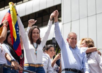 AME6560. CARACAS (VENEZUELA), 30/07/2024.- La líder opositora venezolana María Corina Machado (i) y el candidato a la presidencia de Venezuela Edmundo González Urrutia saludan en una manifestación de apoyo este martes, en Caracas (Venezuela). Miles de venezolanos se han concentrado este martes en Caracas, en un acto convocado por la oposición mayoritaria, para rechazar por segundo día consecutivo lo que consideran es un fraude en los resultados oficiales del Consejo Nacional Electoral (CNE), que en la víspera proclamó a Nicolás Maduro como presidente reelecto con el 51,2 % de los votos. EFE/ Ronald Peña R.