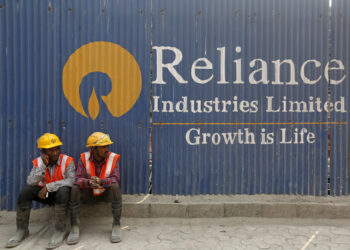 FILE PHOTO: Labourers rest in front of an advertisement of Reliance Industries Limited at a construction site in Mumbai, India, March 2, 2016. REUTERS/Shailesh Andrade/File photo