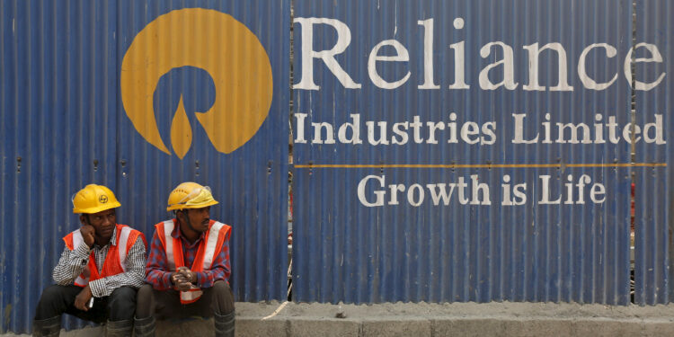 FILE PHOTO: Labourers rest in front of an advertisement of Reliance Industries Limited at a construction site in Mumbai, India, March 2, 2016. REUTERS/Shailesh Andrade/File photo