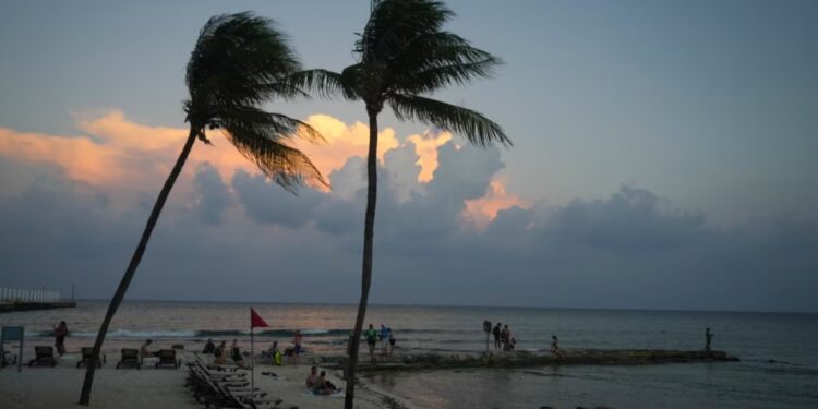 Gente en la playa mientras se pone el sol antes de la llegada del huracán Beryl en Playa del Carmen, México, el miércoles 3 de julio de 2024.