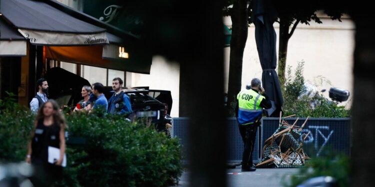 Security stand next a damaged vehicle near the bar "Le Ramus" where a motorist drove onto the terrace of a cafe, leaving several injured, in Paris on July 17, 2024. - A police source told AFP that the investigation into the car that ploughed into the terrace of a bar in Paris on July 17, killing one and injuring six people, is currently focusing on a road accident. (Photo by IAN LANGSDON / AFP)