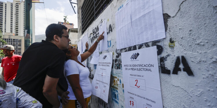 AME5617. CARACAS (VENEZUELA), 28/07/2024.- Ciudadanos venezolanos buscan su mesa de votación durante la jornada de elecciones presidenciales de Venezuela este domingo, en Caracas (Venezuela). El CNE informó este domingo que, sobre las 08.00 hora local (12.00 GMT), el 95 % de los 15.797 centros de votación ya estaban abiertos -dos horas más tarde la hora oficial fijada para la apertura- y computando los votos de personas que acudieron desde muy temprano a las urnas. EFE/ Henry Chirinos