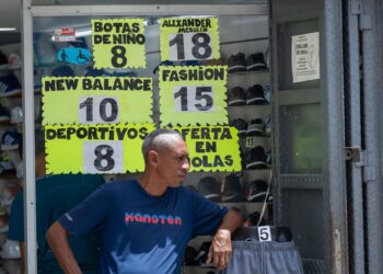 AME464. CARACAS (VENEZUELA), 09/07/2024.- Un hombre espera afuera de una tienda de zapatos donde se ven los precios, el 8 de julio de 2024, en Caracas (Venezuela). La inflación en Venezuela, que en junio cayó hasta el 1 %, se ha desacelerado a raíz de una política para estabilizar el precio del dólar -divisa usada en el país para cotizar bienes y servicios-, para lo que también se han "sacrificado" salarios y créditos bancarios, advierten expertos. EFE/ Ronald Peña