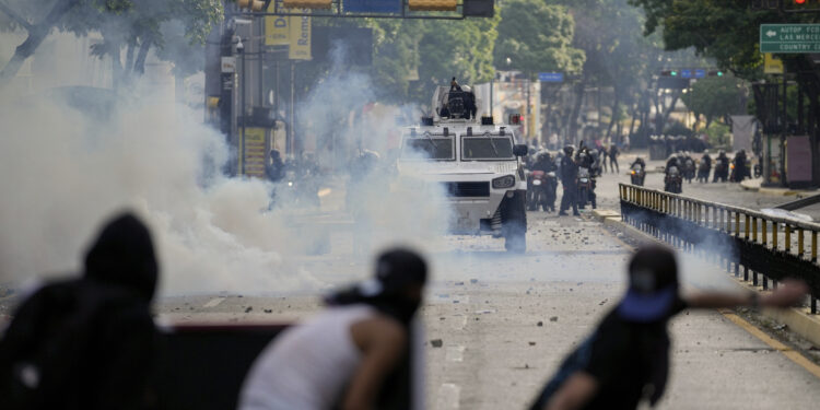 Manifestantes se enfrentan a la policía en las protestas contra los resultados de las elecciones que dieron por ganador a Nicolás Maduro, el día después de las votaciones en Caracas, Venezuela, el lunes 29 de julio de 2024. (AP Foto/Matías Delacroix)