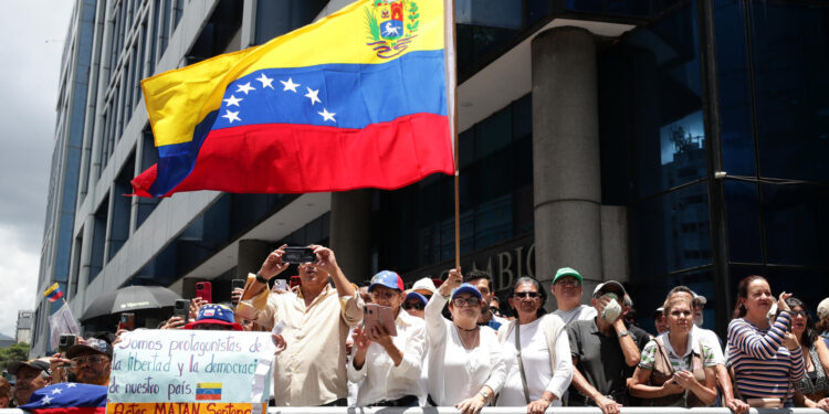 AME3975. CARACAS (VENEZUELA), 28/08/2024.- Una seguidora de la líder opositora venezolana, María Corina Machado, agita una bandera en una manifestación este miércoles, en Caracas (Venezuela). Machado aseguró que "ni un solo Gobierno democrático del mundo ha reconocido" la reelección de Nicolás Maduro, cuyo triunfo en las presidenciales del 28 de julio considera un "fraude", igual que buena parte de la comunidad internacional. EFE/ Ronald Peña