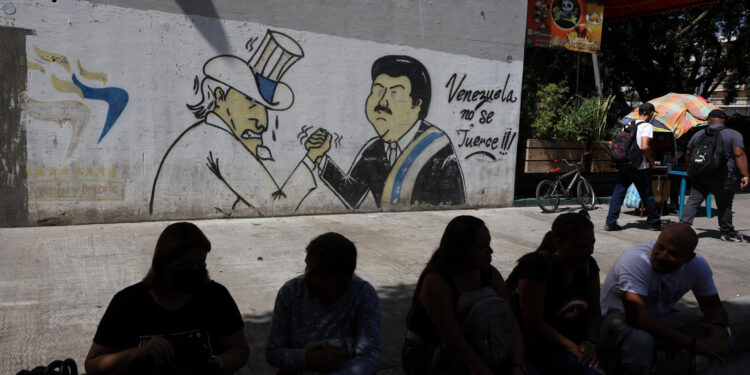 AMDEP5377. CARACAS (VENEZUELA), 30/08/2024.- Personas esperan frente a un mural durante un apagón nacional este viernes, en Caracas (Venezuela). El Gobierno de Venezuela acusó a la oposición aglutinada en la "extrema derecha" del "sabotaje eléctrico" que, según las autoridades, fue la causa del apagón que este viernes enfrenta el país caribeño desde las 4:50 hora local (8:50 GMT). EFE/ Miguel Gutiérrez