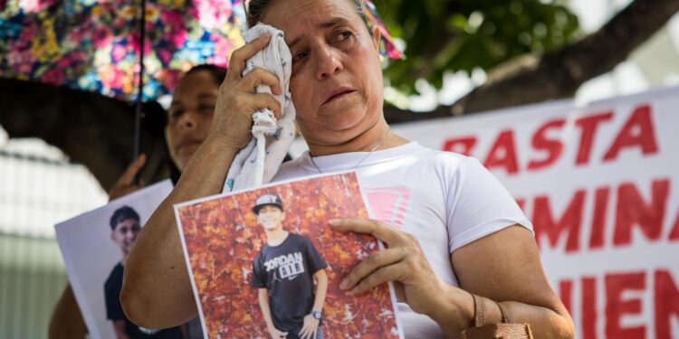 -FOTODELDÍA- AME692. CARACAS (VENEZUELA), 18/09/2024.- Una mujer llora mientras sostiene una fotografía durante una manifestación y recolección de insumos para familiares presos este miércoles, en Caracas (Venezuela). Un grupo de familiares de los adolescentes detenidos en Venezuela denunció este miércoles que los menores sufrieron "torturas" en los centros de detención, a donde fueron trasladados después de ser aprehendidos en el contexto de la protestas contra el resultado de las elecciones del 28 de julio, que ratificó a Nicolás Maduro como presidente electo. EFE/ Miguel Gutiérrez