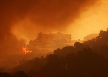 Smoke and flames engulf a hillside near homes (R) during the Airport Fire near Lake Elsinore, California, on September 10, 2024. - Out-of-control wildfires surrounding Los Angeles continued to grow on September 10, forcing families to evacuate and blanketing the sky with choking smoke. The fast-moving Airport Fire in Orange County has consumed more than 9,000 acres (3,600 hectares) since it was started accidentally on Monday afternoon by workers operating heavy equipment. (Photo by David SWANSON / AFP)