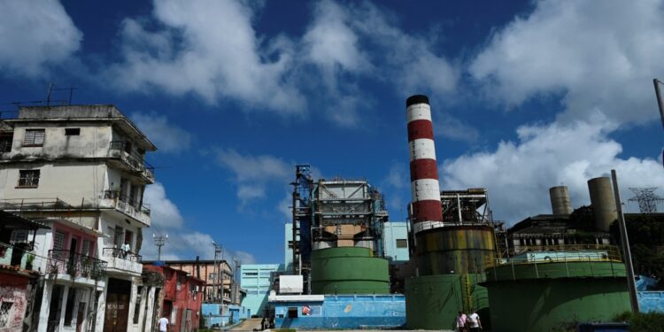 People walk past the Otto Parellada thermoelectric power plant in Havana on October 22, 2024. - Seventy percent of Cuba's population now has power, four days after a nationwide blackout triggered by the collapse of the island's largest power plant, and as the country recovers from Hurricane Oscar, the government said Tuesday. (Photo by YAMIL LAGE / AFP)