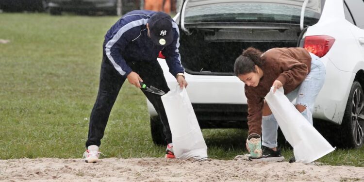 Ciudadanos en la Florida ponen bolsas de arena para apaciguar lluvias ante la amenaza del huracán Milton. | Foto: AFP