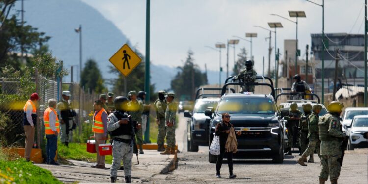 Members of the National Guard and Mexican soldiers watch the entrance after an explosion in a tower of the Aceros Simec complex in the municipality of Xalostoc, State of Tlaxcala, Mexico, on October 30, 2024. An explosion at a steel plant in Mexico's central state of Tlaxcala has left at least 12 people dead, a local official said Wednesday. (Photo by JAIME ANZUREZ / AFP)