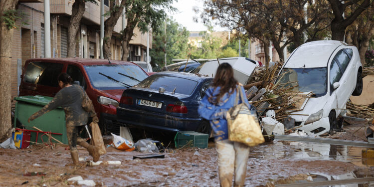 CATARROJA (VALENCIA), 31/10/2024.- Varias personas caminan entre el lodo acumulado en las calles a causa de las intensas lluvias caídas por la fuerte dana, este jueves en Catarroja. Catarroja, una de las localidades afectadas por la dana que asoló este martes la provincia de Valencia, se afana por restablecer los suministros cortados a consecuencia del temporal y en ofrecer ayuda humanitaria a los vecinos.EFE/Manuel Bruque