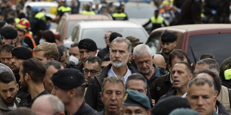 PAIPORTA (VALENCIA), 03/11/2024.- El rey Felipe (c), durante su visita a Paiporta este domingo. Gritos de 'fuera', así como lanzamiento de barro, están recibiendo a la comitiva de los reyes de España, el presidente del Gobierno, Pedro Sánchez, y el president de la Generalitat, Carlos Mazón, a su llegada al centro de Paiporta. Numerosas personas indignadas han recibido con insultos a la comitiva y se han encarado con ella, mientras que tanto el rey como la reina ha intentado mediar con jóvenes que se les han acercado. EFE/ Biel Aliño