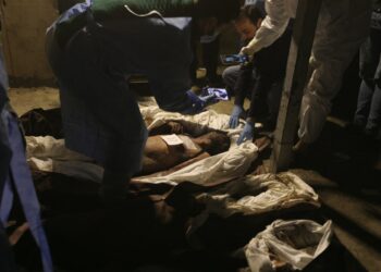 Sanitary servicemen take photos of bodies of dead persons at the morgue of a hospital in Damascus on December 10, 2024. - Rebel fighters found around 40 bodies bearing signs of torture inside Harasta hospital morgue near Damascus on December 9, 2024 stuffed into white body bags with names and numbers written on them, a combattant told AFP. The Syrian Red Crescent transported the bodies to a Damascus hospital, so that families can come and identify them. (Photo by Abdulaziz KETAZ / AFP)