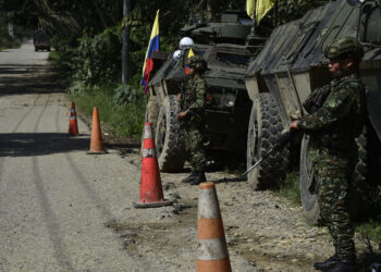 Army soldiers stand guard on a road as forces patrol in Tibu, Norte de Santander province, Colombia, on January 21, 2025, after recent clashes between rival left-wing guerrillas. Colombia vowed "war" against left-wing guerrillas Monday, declaring a state of emergency and deploying thousands of soldiers to contain violence that killed at least 100 people and threatens to scupper the country's fragile peace process. (Photo by Schneyder Mendoza / AFP)