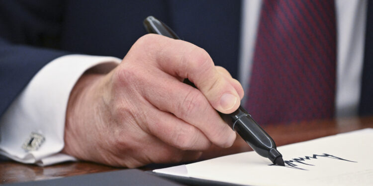 US President Donald Trump signs an executive order in the Oval Office of the White House in Washington, DC, on January 23, 2025. (Photo by ROBERTO SCHMIDT / AFP)