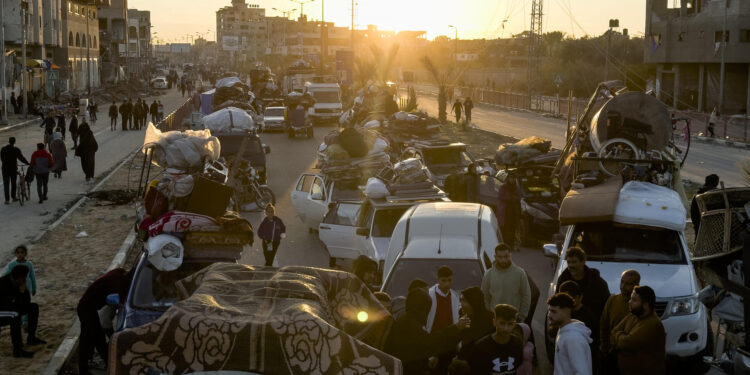 NUSEIRAT (GAZA), 25/01/2025.-Cientos de gazatíes, muchos de ellos cargando en brazos la misma lona y cuerdas que han usado como refugio en el sur de Gaza durante la guerra con Israel, aguardan en Nuseirat (centro) el momento que el Ejército israelí les deje atravesar el Corredor Netzarim y regresar al norte de la Franja.EFE/Stringer