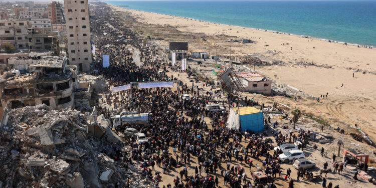 People walk along Gaza's coastal al-Rashid Street to cross the Netzarim corridor from the southern Gaza Strip into the north on January 27, 2025. Displaced Palestinians began returning to northern Gaza on January 27, an official at the territory's Hamas-run Interior Ministry told AFP, after a breakthrough in negotiations between Hamas and Israel. (Photo by Omar AL-QATTAA / AFP)