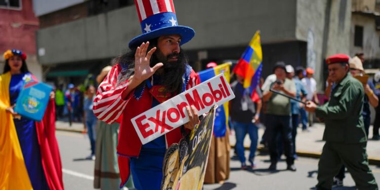 ARCHIVO - Un hombre vestido como el personaje estadounidense Tío Sam sostiene un cartel de la petrolera Exxon durante una marcha por el Esequibo, en Caracas, Venezuela, el 26 de septiembre de 2023.