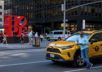 A yellow cab taxi driver pauses and looks at his phone on September 01, 2022 in New York. (Photo by ANGELA WEISS / AFP)