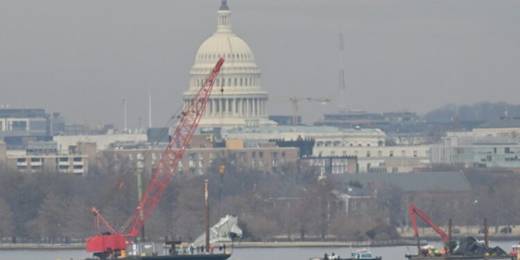 A crane removes airplane wreckage from the Potomac River, where American Airlines flight 5342 collided with a US Army military helicopter, near Ronald Reagan Washington National Airport in Arlington, Virginia, on February 3, 2025. Operations to salvage the wreckage from a deadly collision between a US Army helicopter and a passenger jet continued as rescuers said 55 victims had so far been identified. Dozens of victims have been pulled from the icy Potomac River, and rescuers voiced confidence that those remaining would be retrieved in the massive operation to recover the plane that collided in midair with a Black Hawk military helicopter. (Photo by ROBERTO SCHMIDT / AFP) / ALTERNATE CROP